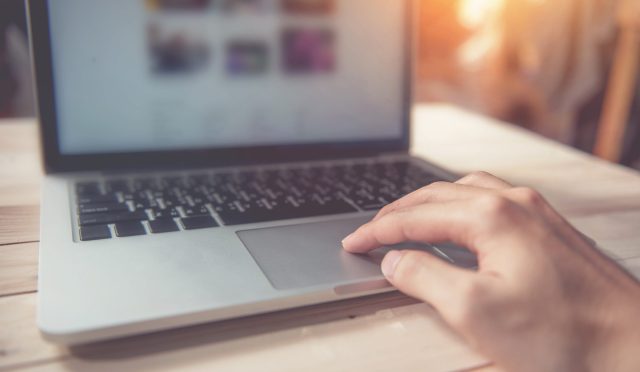 Man hand using touchpad on laptop at home